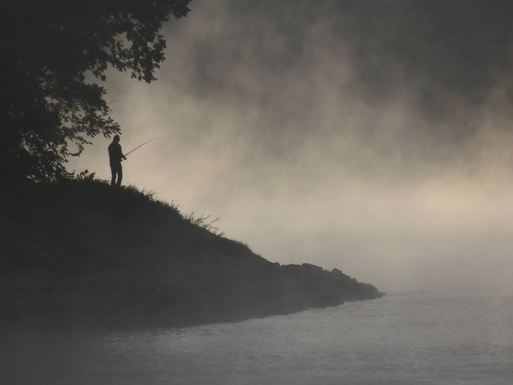 Anglers in jackets on a cold river at dawn, mist rising off the water